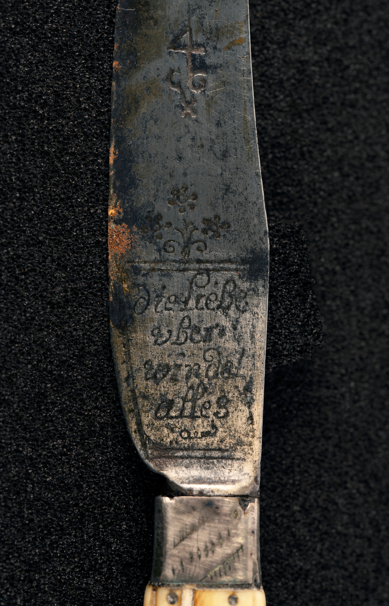 Kniv med beinskaft med metallpryd, blad med inskripsjoner.
