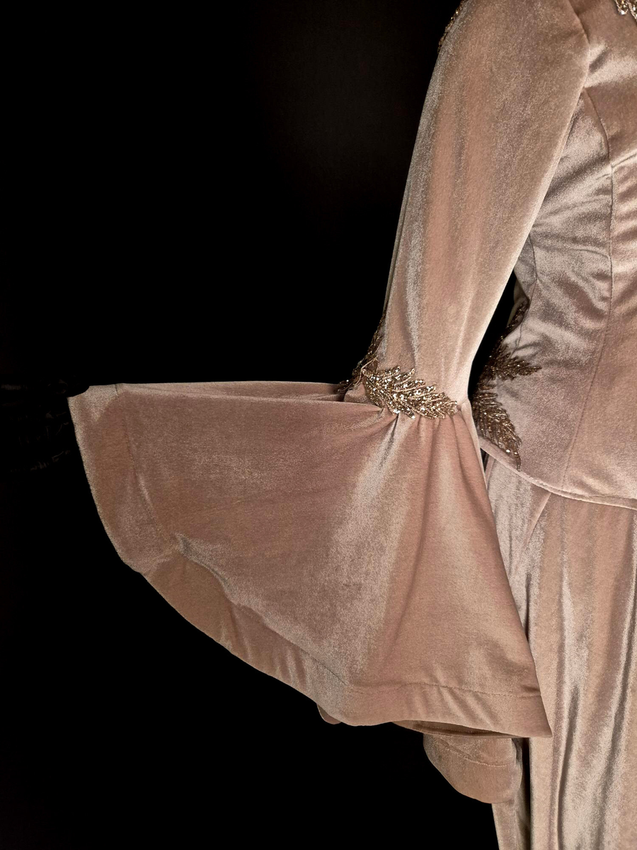 Strukturerad överdel uppsydd i rosa-beige sammetstyg och champangefärgade applikationer samt stenar.  Applikationerna är i form av blommor och löv. Fastklistrade på tyget. De är placerade runt den runda ringningen, lätt nedåt vid axeln samt nedre delen av plagget. Torson är uppdelad i 10 tygpaneler ihopsydda med raksöm, fodrad med ett beige tyg (möjligen baksidan av sammetstyget). Stängda kanaler på insidan för korsettbening.16 stycken totalt.  Nedre kanten av överdelen är benad. Inbyggda kupor. Korsettstängning på baksidan med extra tygstycke för att dölja huden under. Stängningen består av 10 stycken tyg öglor på vardera sidan av överdelen och ett tillhörande band.  

Ärmarna är fästa till överdelen med zick-zack söm. Raka, smala ärmar till armbågen, därefter öppnas de upp till en vid fallande form. Ofodrade vid den smala delen. Den vida delen är fodrad med samma sammetstyg som yttertyget. 
Dom smala delarna är ett tygstycke vardera. De vida delarna är ett separat tygstycke vardera och fästa till resterande ärm med raksöm, lätt veckade. 
Ärmarna avslutas med en fållad kant som innehåller ett stabiliserande mellanlägg. Applikationerna samma som ovan men placerade kring armbågen - där den smala delen av ärmen möter den vida delen. 



