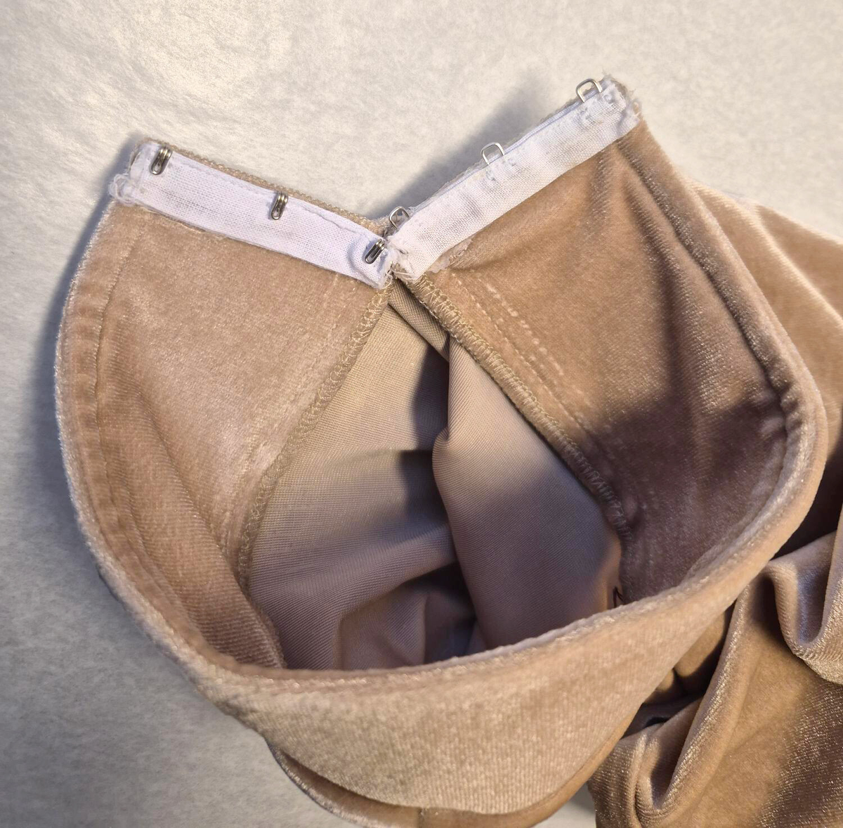 Byxor i harem-modell uppsydda i rosa-beige sammetstyg och champangefärgade applikationer samt stenar. Applikationerna är i form av blommor och löv. Fastklistrade på tyget i en större vertikal form i mitten av byxorna. Ihopsydd med 4 tygpaneler, ej fodrad. Samansatt med raksöm och vid vissa delar overlocksöm. Byxbenen avslutas med muddar som stängs med 2 hakar och hyskor på vardera ben. Muddarna har ett mellanlägg för att ge struktur. Midjan har en kanal för ett vitt snöre som knyts för att dra åt midjan och stänga byxorna. 

