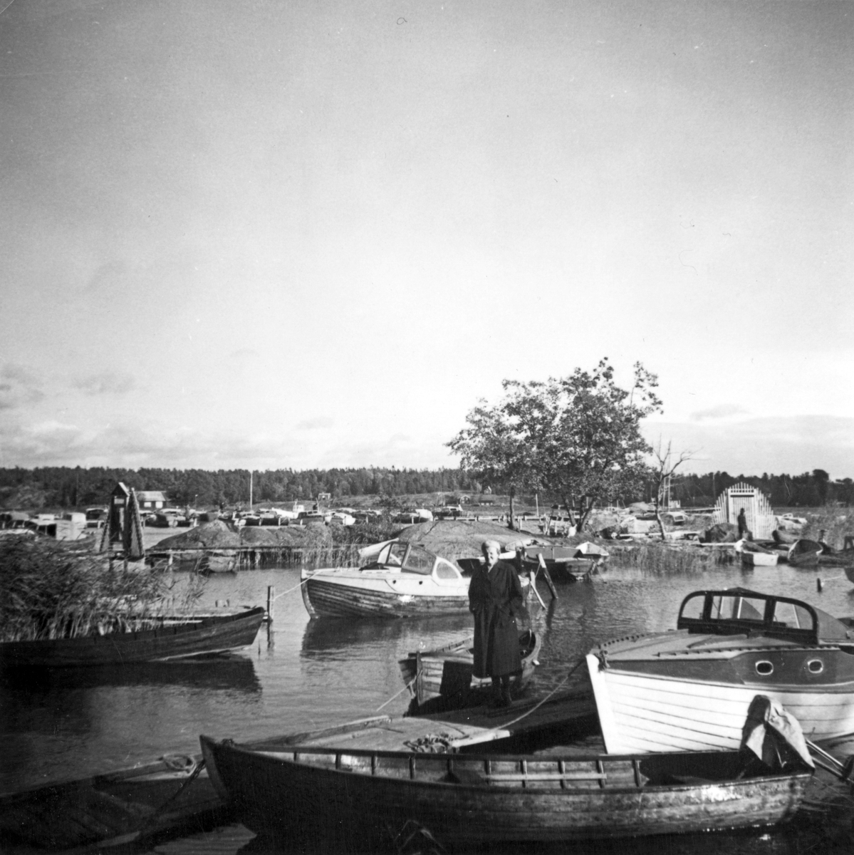 Vid småbåtshamnen, NSS brygga. En kvinna står på bryggan, båtar ligger förtöjda. Bedarön i bakgrunden. 

Sjöfart, fritid.