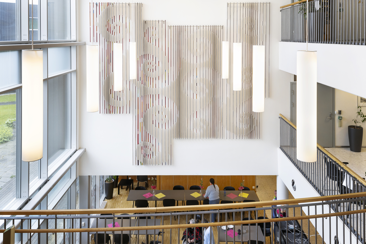 Store, overlappende spiraler som er visuelt knyttet sammen og danner et større, sammenhengende mønster over de forskjellige lamellpanelene.
