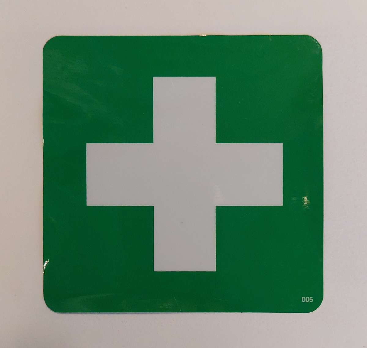 Klisterdekal med vitt kors. Symbol för förbandslåda.