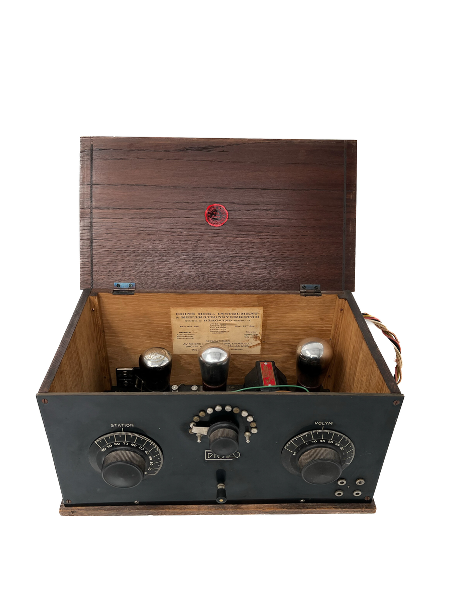 Radioapparat med högtalare.
Högtalaren är tillverkad av Philips ca 1930. Modellnummer 2032. Bakelit. 
Radion i trä, medföljande kopplingschema finns inuti radion. Radion tillverkad av Edins instrument och reparationsverkstad (Edins radio) i Härnösand. 