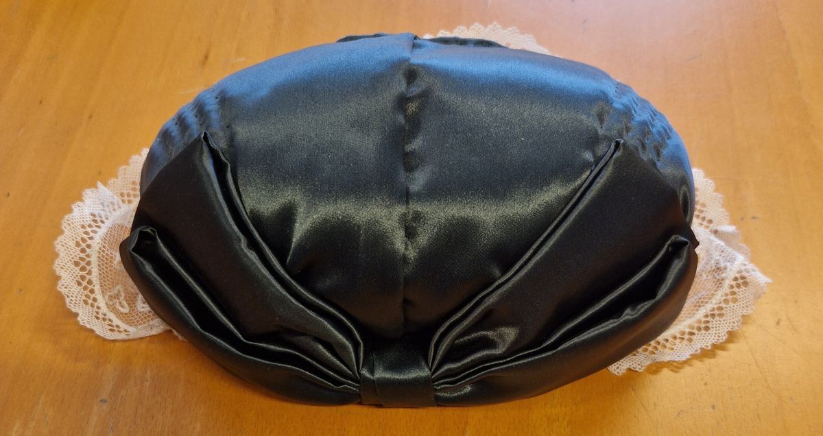 Folkdräkt från Ådals-Liden. Livkjol, överdel, förkläde, halskläde, kjolsäck, mössa, strumpbyxor och skor. Halsklädet, metallspännet på kjolsäcken, strumpbyxorna och skorna är inköpta. Skorna med etikett inuti: "Britta från Wiskania". Svensk kvalitet. Storlek 4½. Kjolsäcken är märkt med initialerna I F, (Ing-Marie Frisendal) och 1954. Gåva av Ing-Marie Hedebrand, Sundsvall. Tillverkad av Ing-Maries syster, Margareta Frisendal.
Anm: Folkdräkten från Ådals-Liden, en del av Ångermanland, har livkjol av helylle med empireskärning, ett vitt linneförkläde (modell södra dräkten) och en bindmössa i rött eller grönt, inspirerad av södra dräkten. Överdelen är en linnesärk med hålsöm vid ärmsluten och en utåtvikt fåll vid halsringningen. 
En kjolsäck, som tillhör dräkten, är gjord av blått ylletyg med applikationer i rött och gult, med ett centralt placerat hjärta och andra dekorativa former. 
Ådals-Lidens folkdräkt är en del av de två typerna av ångermanländska folkdräkter, den södra och den norra, som presenterades av Ångermanlands hemslöjdsförening år 1922. 
Källa: https://www.draktnyckel.se/adalsliden/