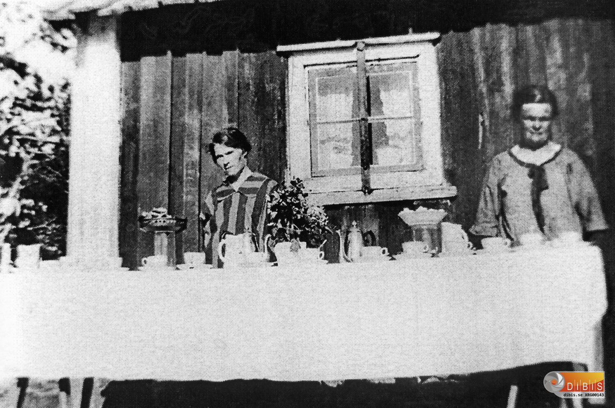Adela Alinder (kallades Adla) 1881-1975 och Edit Gustafsson född Berggren 1890-1975 ställer i ordning för kaffekalas på Lottasholmen i Söderhamns skärgård. Troligen 1920 eller 1930-tal..
Edit och hennes make Ivar Gustafsson var mycket aktiva inom IOGT. Logen (eller föreningen som det heter i dag) var ofta ut till ön på träffar. Kanske var det här ett sådant tillfälle.
