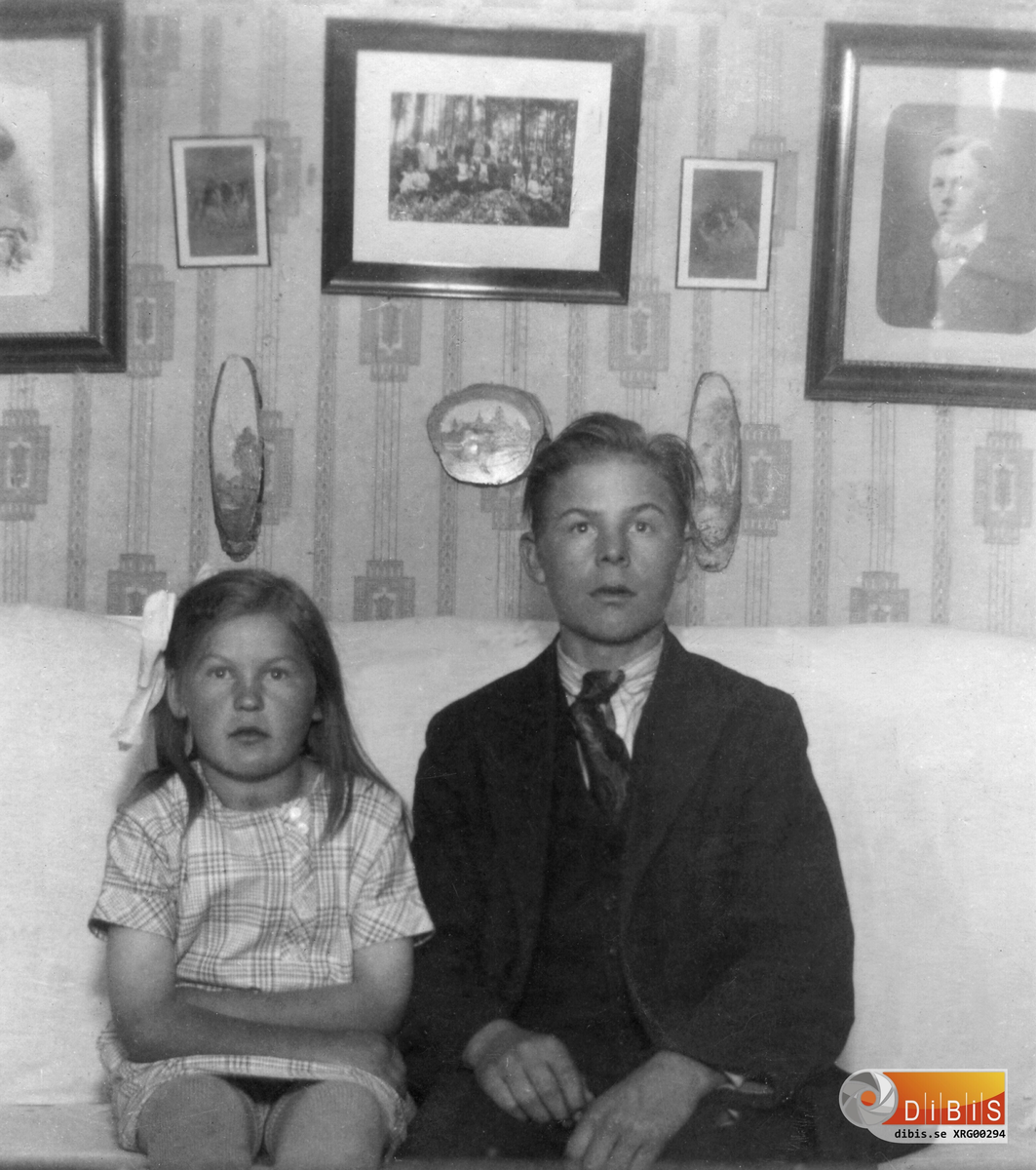 Elsy Gustafsson (1916-2008) sedermera gift Ohlin. Brodern Enar Gustafsson (1909-1973).
På tavlan till höger ses deras far Ivar Gustafsson.
