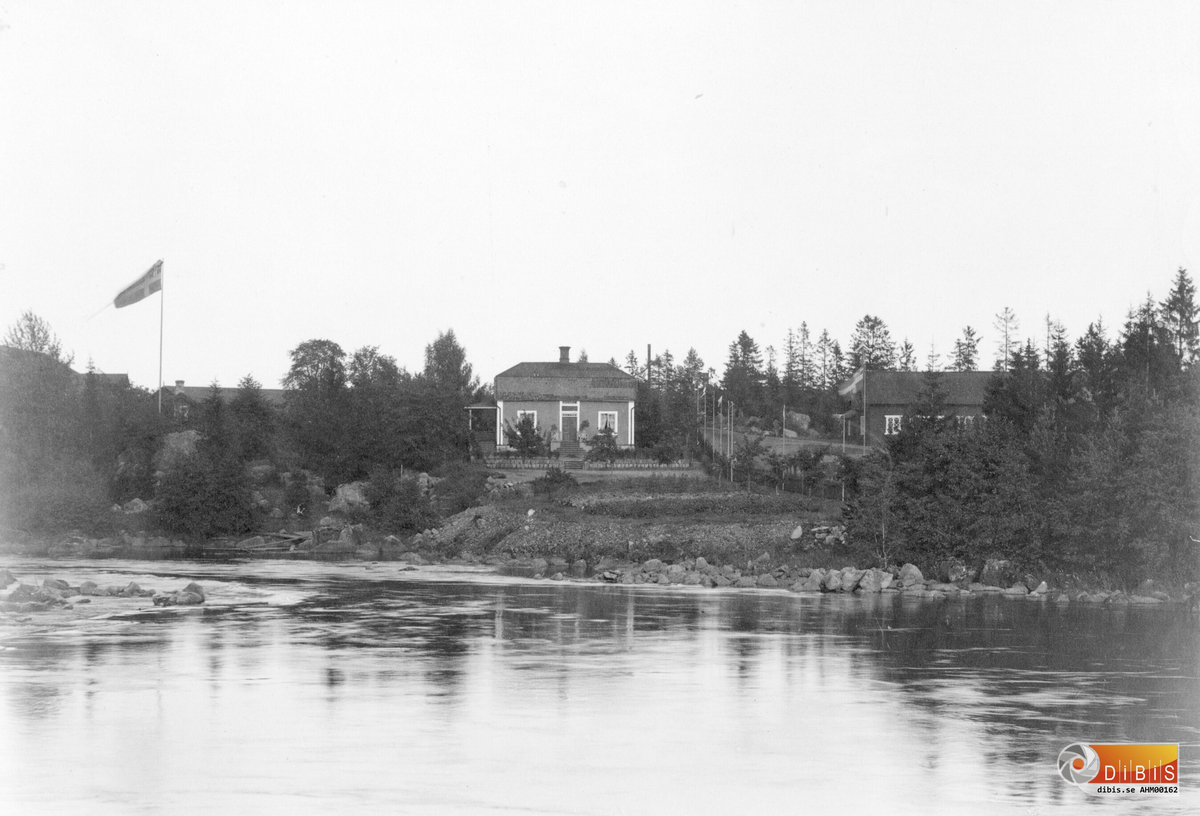 Smidesmästarbostaden på Söder i Ljusne, fotograferat från gamla träbron.
Till höger, Stallbacken med stall m.m.
Nedanför Smidesmästarbostaden, ser man en gammal slaggstensmur som fortfarande finns (2019).
Man kan skymta en väg mellan byggnaderna, till höger om Smidesmästarbostaden, med flaggor efter vägen kanske är det fotograferat i samband med kungabesöket av Oscar II 1890.