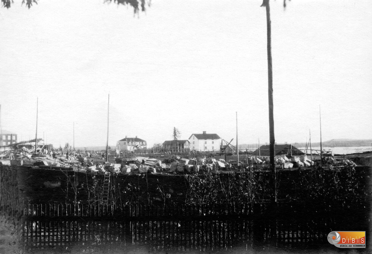 Motiv från Ellerviksvägen 18 okt 1927.
Byggnaden med valmat tak mitt på bilden är sågverkets förmanskasern, den köptes av Johan Israelsson som river den och bygger upp den bredvid skolan uppe på samhället.
Vita byggnaden till höger är föredetta kolarkasern nu under fabriksbygget används den som  logement för byggarbetarna..