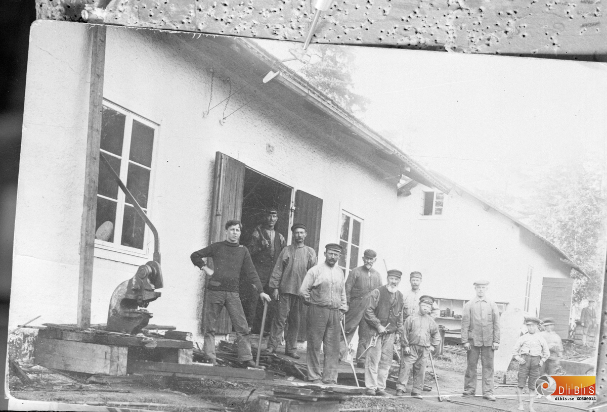 Smeder och släggdrångar utanför smedjan som existerade fram till 1916. Smedjan flyttade då in i en del av sågens verkstad.