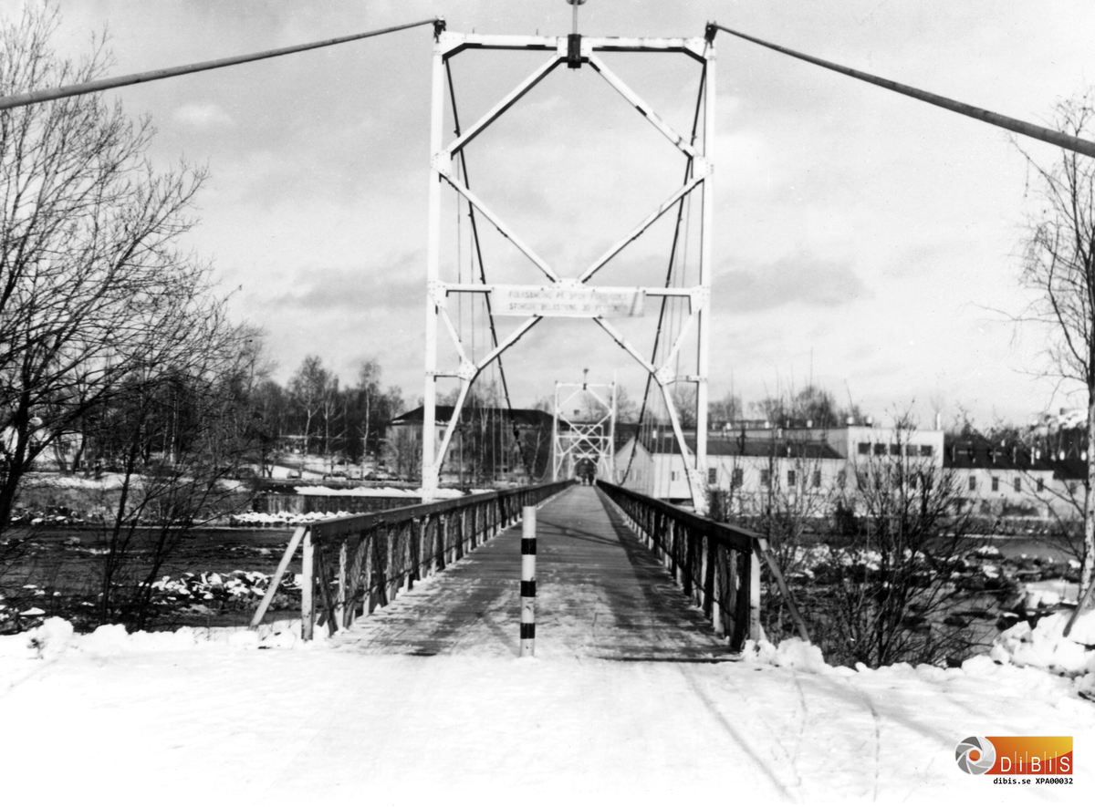14-2 1973
Hängbron över Ljusnan. Brukskontoret och  Kättingfabriken syns på andra sidan älven.
Bron byggdes åren 1936-37 i samband med
Södra kraftstationen.
