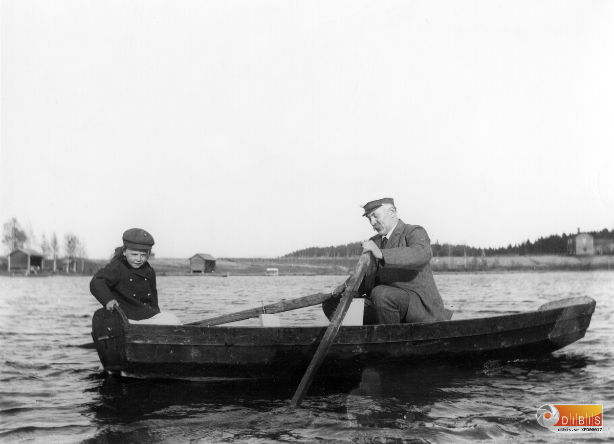 Per Lind och en flicka i en eka på Föltjärn i Östra Höle.
I bakgrunden ser man Lapphagen och Skidtjärnsberget.
Längst till höger Österstuga (se även bild XPD 00018)