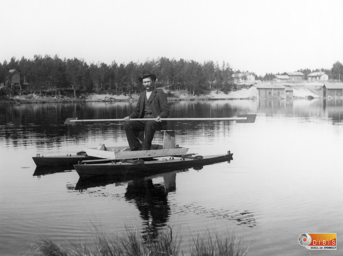 Bilden tagen från Smelinds brygga. Mannen i kanoten är okänd.
Huset längst till vänster är Murars härbre. Till höger vid sjöstranden står Brolins smedja och Jonanders linbod.
Gårdarna är Högkvists till vänster och Björkens till höger.