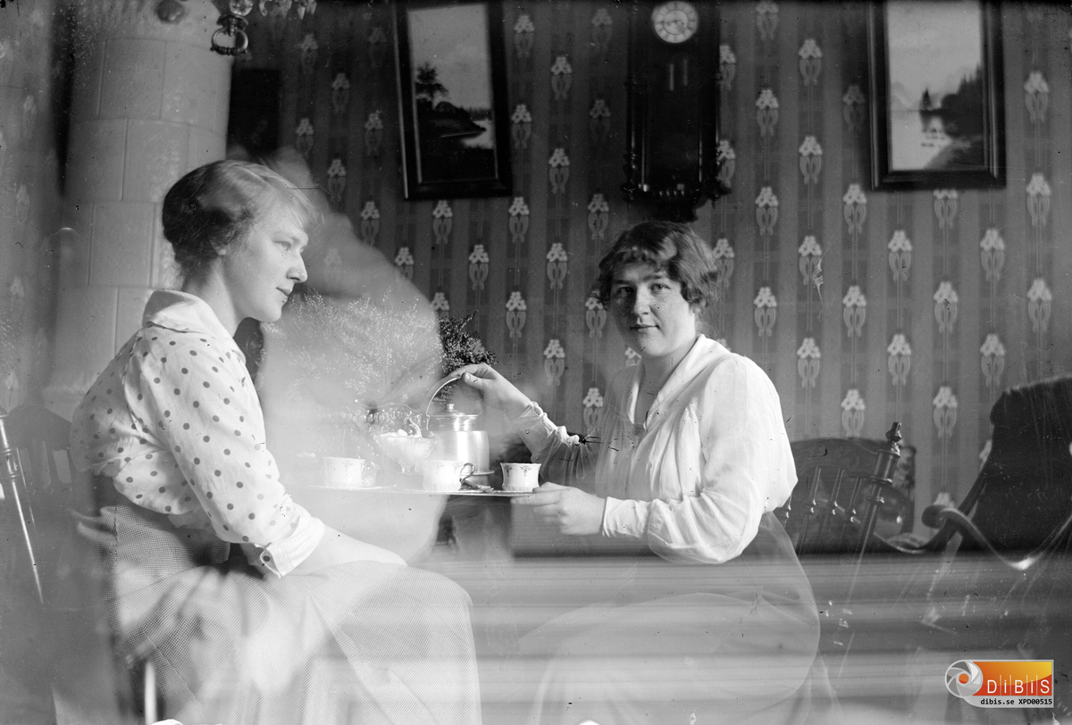 Två kvinnor sitter vid ett bord och dricker kaffe.