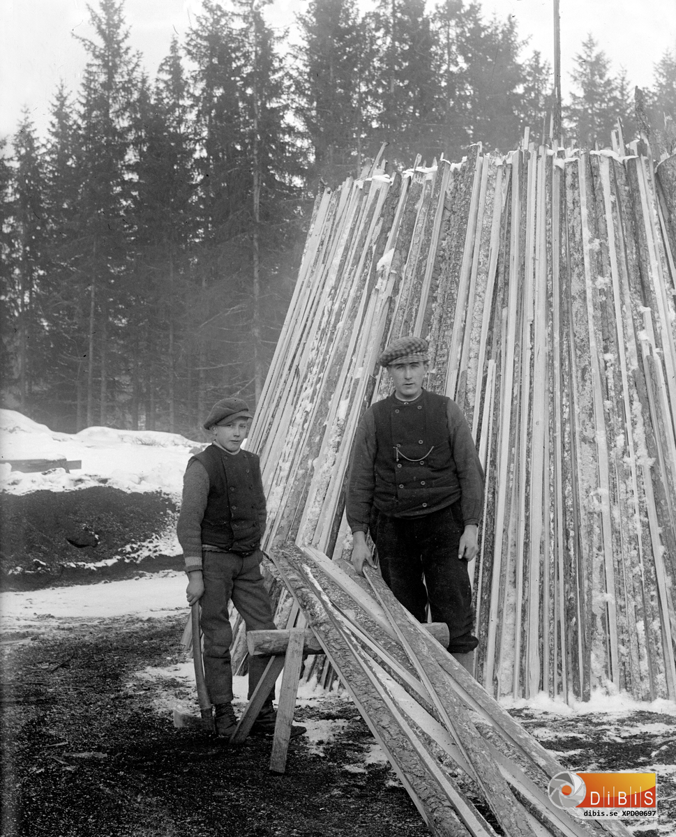 Höle såg, vid kolningen.
Lars Larsson t.h och Holger Vestberg reser en mila av ribb och bakar, omkring 1920