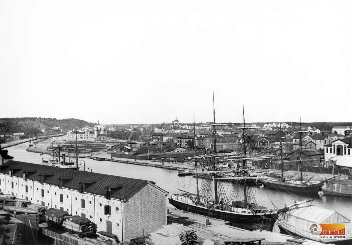 Vy från Faxeholmen över Söderhamn.
Kyrkan mitt i bild. I förgrunden segelfartyg och en lastpråm