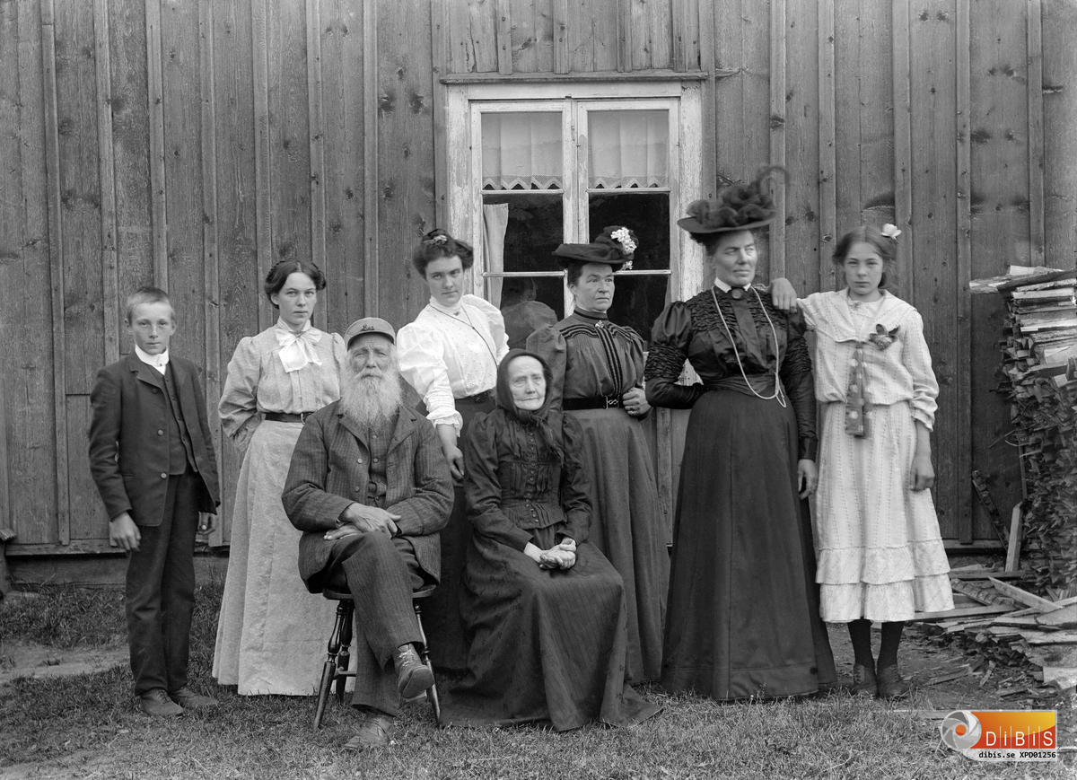 Familjen Smelinds framför sitt köksfönster.
Övre raden från vänster:
Herman Lind
Märta Lind
Jenny Lind
Tilda Lind fru till Per Lind
Marta Bengtsson från Glössbo
Maria Lind
Sittande Jonas Lind och Margta Andersdotter föräldrar till Per Lind.