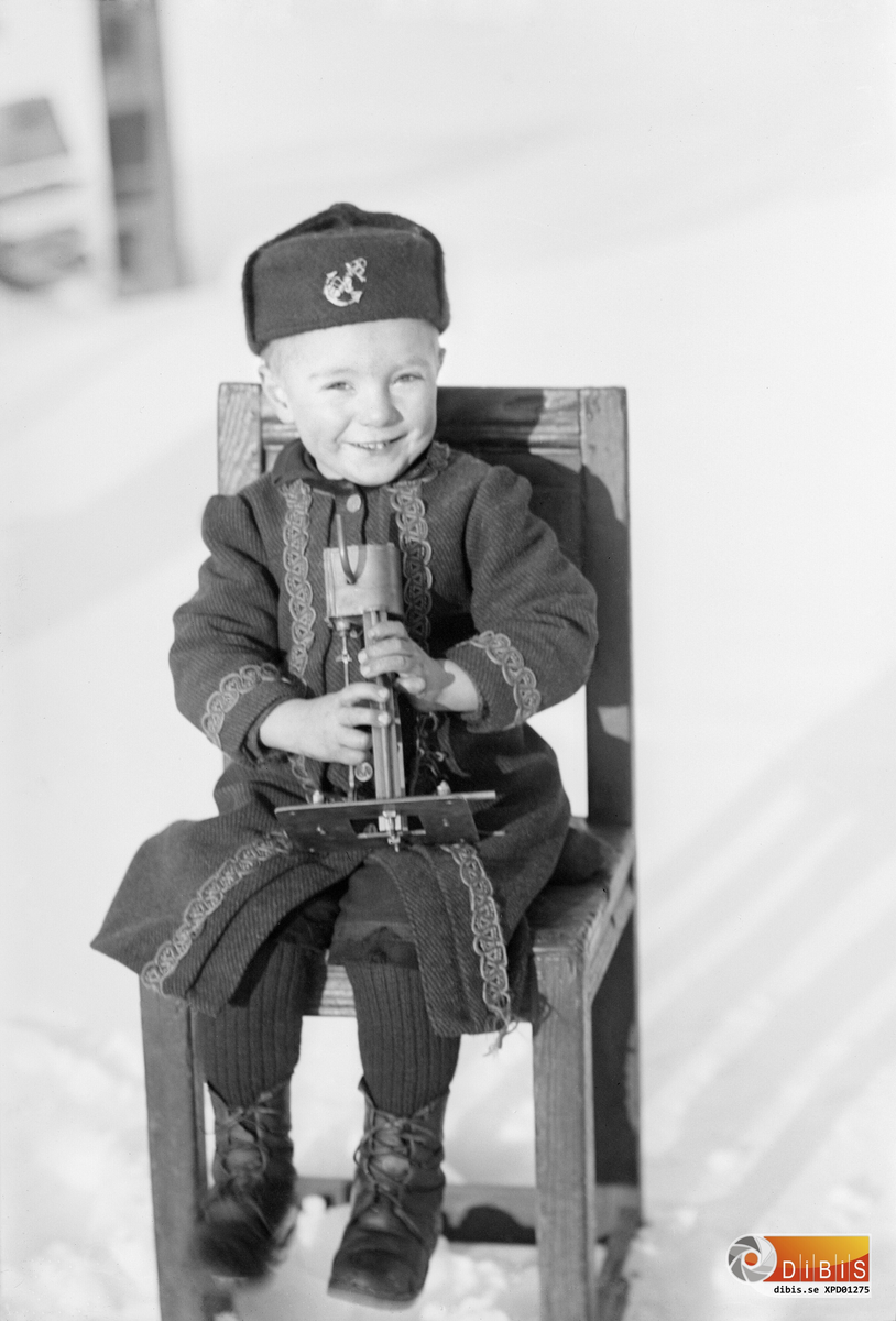 Smelinds Herman Lind sitter på en stol med sin leksak i handen omkring 1897-98.
