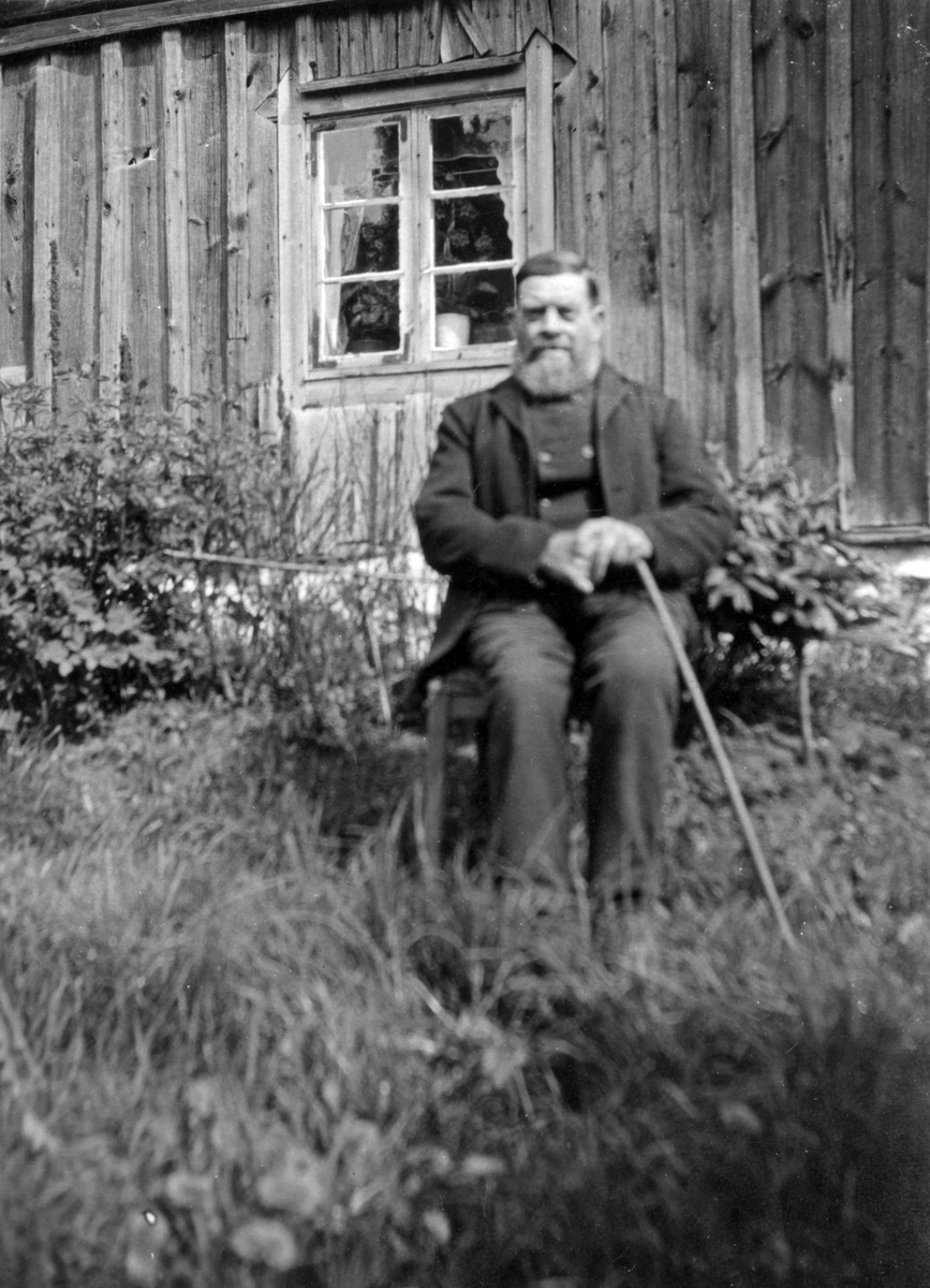 Johan Larsson sitter framför stugan i Sandhagen.

Personer på bilden:
Johan Larsson (född 1845 i Spånga, död i Ösmo 1931)