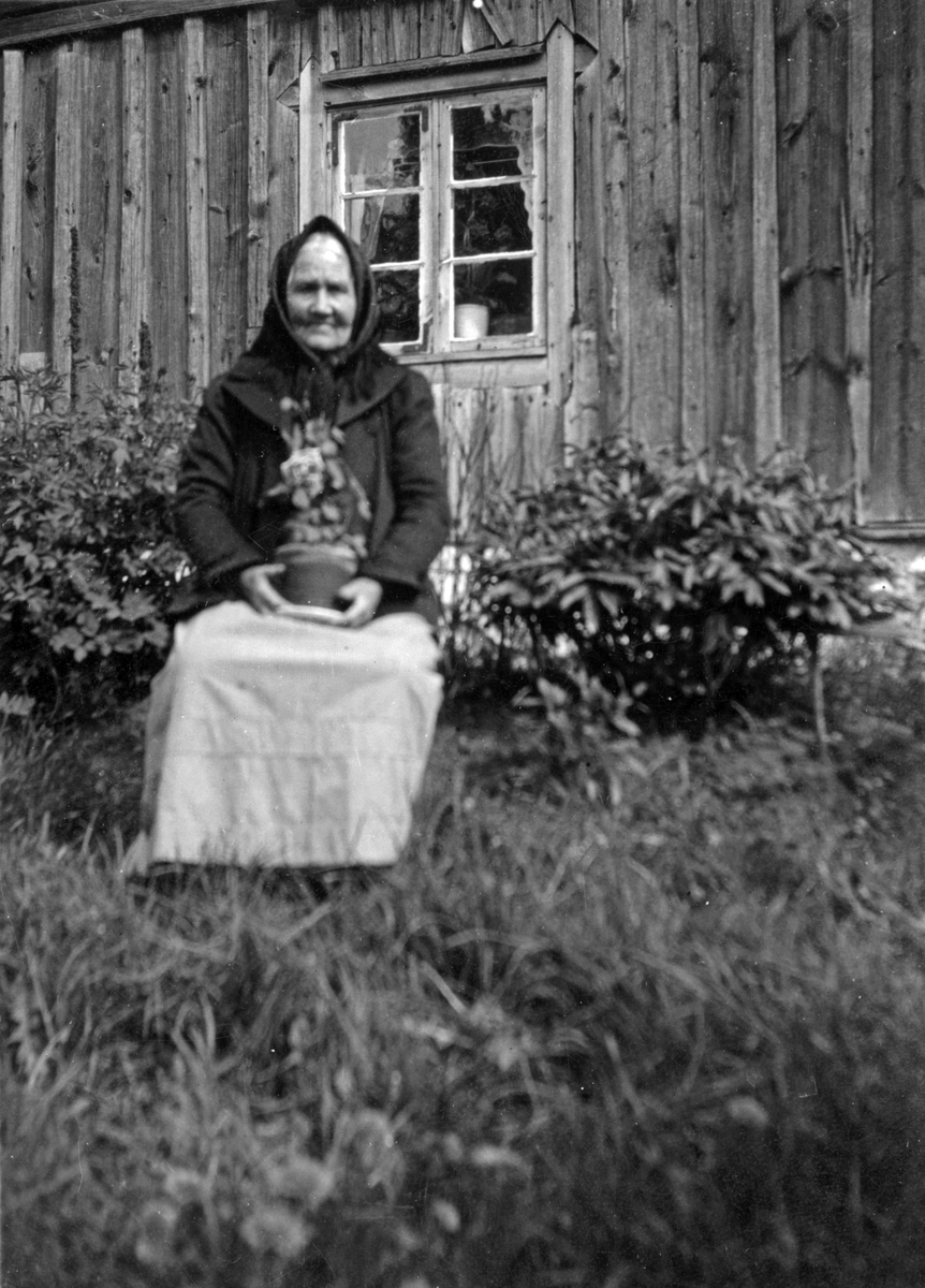 Sofia Blom sitter framför stugan i Sandhagen.

Personer på bilden:
Sofia Christina Blom gift Larsson (född 1852 på Muskö, död 1938 i Ösmo).