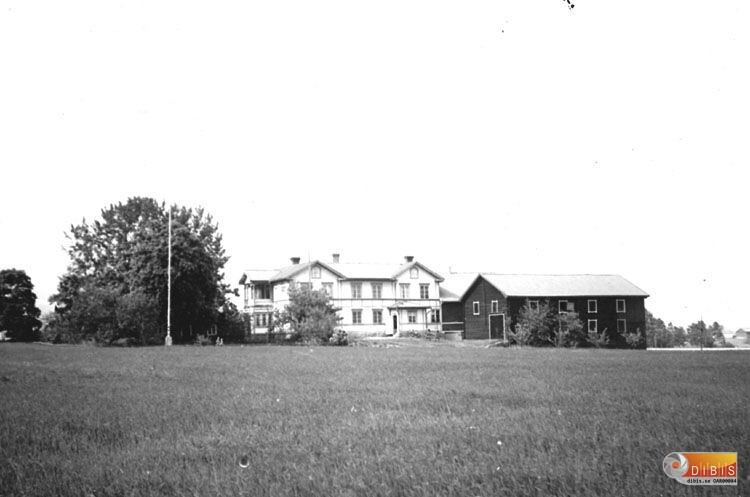 Stort vitt bostadshus med uthus.