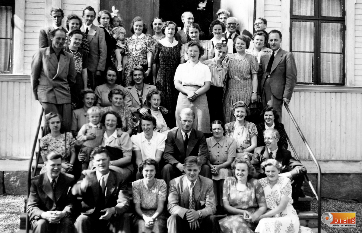 Gruppen samlad på trappan till Hudiksvalls missionskyrka. Det handlar om en sångarresa med buss och ett framträdande i Hudiksvall. Deltagarna kommer från församlingarna i det som hette Söderala Missionsförbund. Det betyder att gruppen har deltagare från Söderala, Marmaverken, Vansäter och Bergvik. Inte minst Bergvikskonferensen hade gjort de här sångarna och musikanterna välkända.
Bussresorna gjordes med bussar från Bröderna Olssons i Mokorset. Oftast var det Per Olsson, Buss-Per, som körde. Resorna kunde gå till platser som Sundsvall eller till församlingar i Gästrikland. Vanan att hälsa på andra församlingar fanns sedan tidigt 1900-tal. Det finns bilder bevarade från resor med Bäckfors Möblers lastbil som under helgerna försågs med ett bussliknande bygge på lastbilsflaket. Såväl lastbilen, en Volvo, som busschassiet var uppställda på Zetterstens gård i Verkmyra under krigsåren. Bilen blev därefter Epatraktor hos Ellners på Norrhäll i Vansäter. Busschassiet kunde inte användas till annat än  lekstuga men skrotades så småningom.
Eftersom året är 1946 kan man utgå från att stämningen var extra god ett år efter krigsslutet. Privatbilismen hade inte tagit fart och det var buss om gällde det här året och flera år framåt.
Namnlistan är inte komplett därav några frågetecken.
Första raden från vänster:
Algot Björklund, Anders Selin, Verna Jonsson, Erik Skoglund, Margit Skoglund,
? Wiik.
Andra raden:
Najmie Jansson, Sigrid Björklund med sonen Thore, Astrid Lindblom, Henning Åslund, Elsa Åslund,
Anna-Lisa Jonsson, Lilly Björklund, Einar Jonsson.
Tredje raden:
Tre damer sittande:
Inga-Britt  Forsell, Anna-Lisa Englund/Lundin, ??
Fjärde raden:
Olle Wiklund, Ingrid Bergström, född Öhrn, Jenny Forsell, Tora Jonsson, Greta Jonsson, Malvina Skogman, Edith Skogman, Ruth Nilsson, Holger Nilsson.
Bakre ledet från vänster:
Bengt Schön, Märta Jonsson, Petrus Zettersten, Lilly Björklund med dottern Monica,
Ruth Hall, Naime Löfstedt, Mildred Ellner, Gottfrid Skogman, Ruth Larsson, ? Ekstrand,
Lars Nilsson, Leo Ekstrand och Johannes Palm.