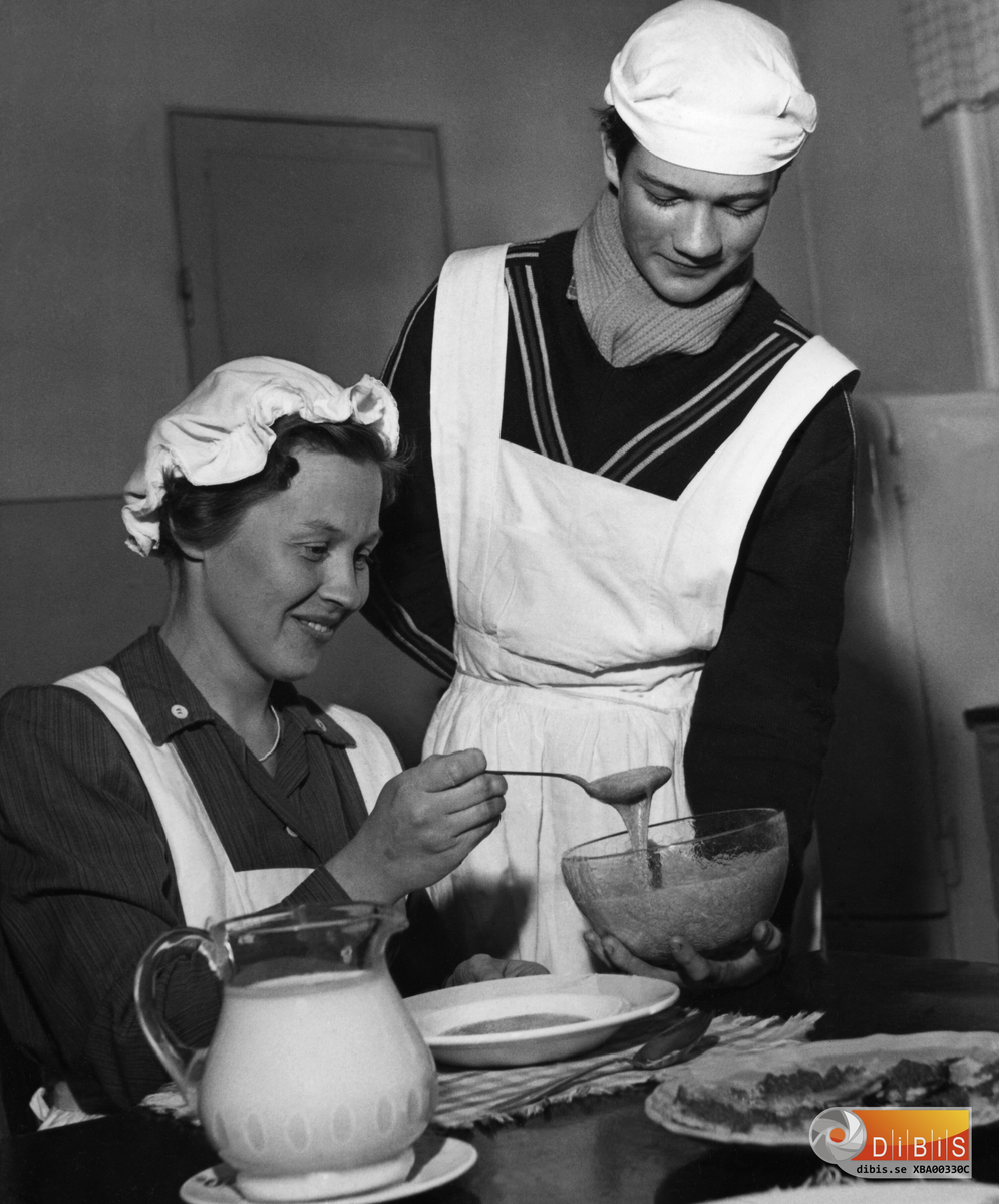 Avgångsklass 1956. Skolkök på samstugan Läraren Barbro Gärdebo noterar att eleverna lagat anvisade rätter. Kjell Persson serverar.