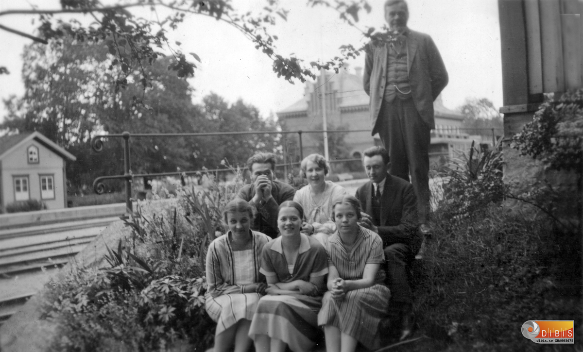 Samuel-August Blomqvist på trappan till tjänstebostaden i Söderhamn. Bangården och stationshuset skymtar i bakgrunden.
På trappan sitter från vänster döttrarna Elsa, Karin och Ruth samt bakom dem Helga som gifte sig med Paul Blomqvist.Hon sitter mellan, från vänster Nils Larsson, Lynäs, Bergvik, och Petrus Zettersten, Verkmyra, Bergvik. Båda blivande mågar till S-A Blomqvist. Sonen Paul saknas på bilden. Det troliga är att han tog bilden.