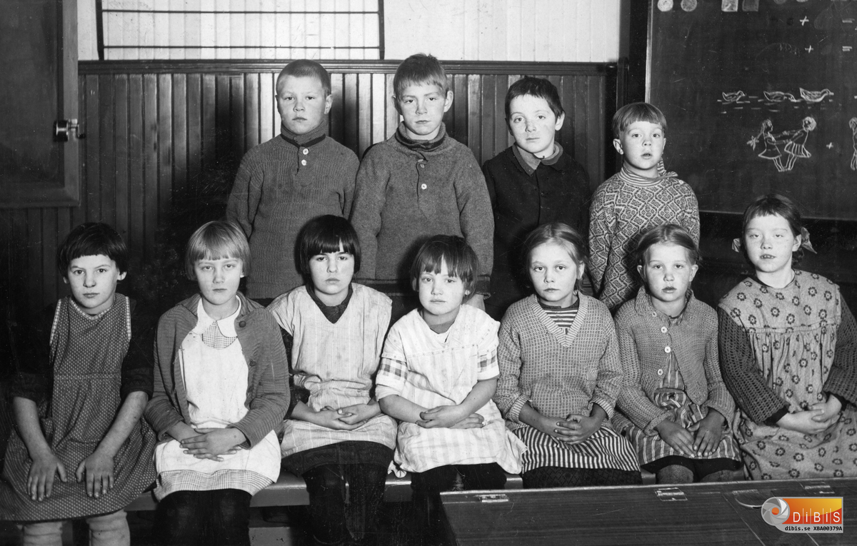 Eleverna befinner sig i Lynäs skola, Bergvik. Längst fram till vänster sitter Greta Lindberg, Verkmyra, Bergvik, dotter till Marta och Karl Lindberg. Hon kom senare att ingå äktenskap med Harry Strandberg, bosätta sig i Lynäs by och få sonen Holger.