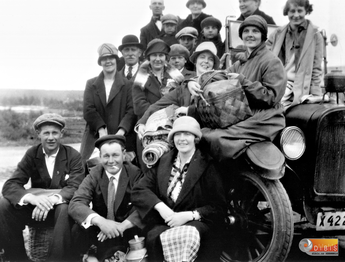 En sommarsöndag någon gång i slutet av 1920-talet drog familjerna Lindblom och Bergstrand på utflykt eller kanske bärplockning. Man var i alla fall välförsedd med mattor att sitta på, en rejäl mjölkkruka med vatten, på motorhuven står en märkvärdig pjäs som nog gick att koka kaffe i.
Bredvid matthållande Anna Bergstrand sitter hennes syster Greta Östansjö med en stor korg som säkert är välfydd med godsaker. Bilen är en av Gustaf Bernhard Lindbloms två lastbilar. Det här är Chevroleten, ett riktigt vrak, medan den något piggare T-Forden tydligen var ute på andra uppdrag.
På lastflaket riggades två bänkar upp med ryggarna mot varandra, typ militärtransport, och sedan uppsittning kommenderats bar det iväg, med barnen i förarhytten kan man hoppas. Resorna gick ofta till Gullgruva eller till trakten av Långkässlingen.

Hans Lindblom
