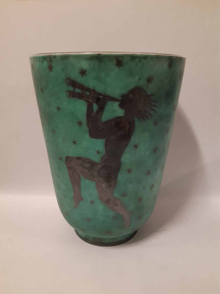 Stor vas i argenta med silverdekorationer föreställande tre dansande musikanter mot grön glasyr, en spelar dubbelfjölt, en spelar lyra och den sista spelar cymbaler.
