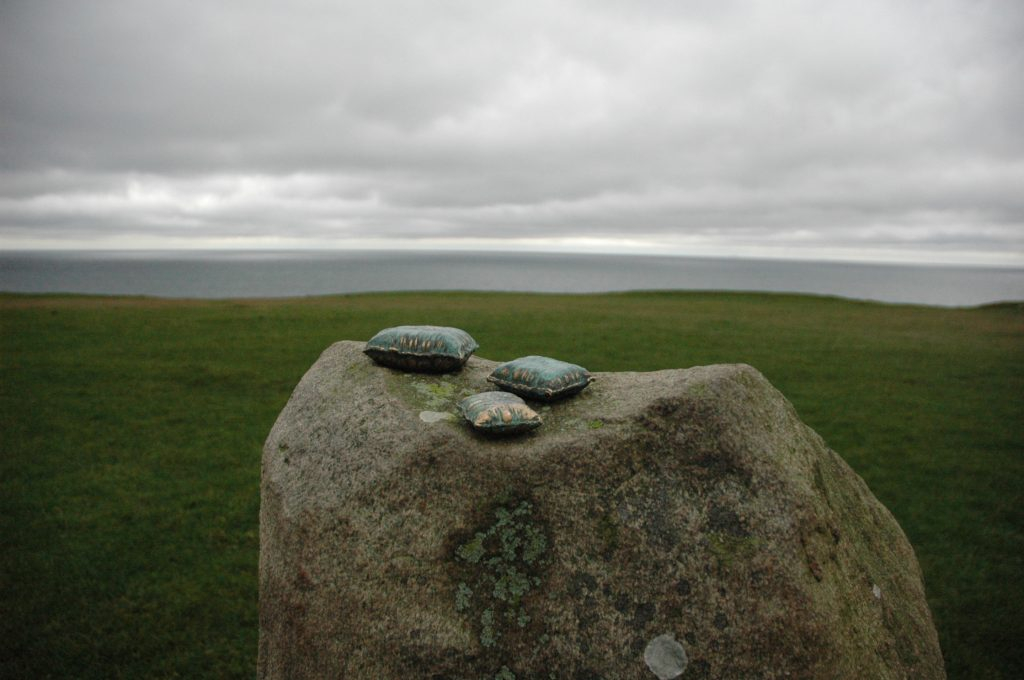 REM består av tre miniatyrskulpturer i brons, formade som kuddar – symboler för övergångar mellan verklighet och dröm. Varje kudde bär på en berättelse om bronsens eviga kretslopp: från konst och kyrkklockor till krigets kanoner, och tillbaka till konsten.

Här vilar drömmar, fångade i bronsens tyngd och tidlöshet, en påminnelse om att det dolda och oupptäckta alltid väntar på att upptäckas.heten att vara den/det man är.

Skulpturen monteras på en aluminiumplatta som fästs med två skruvar. Underlaget behöver en fördjupning, sedan limmas med epoxylim – förslagsvis på sten eller betong.