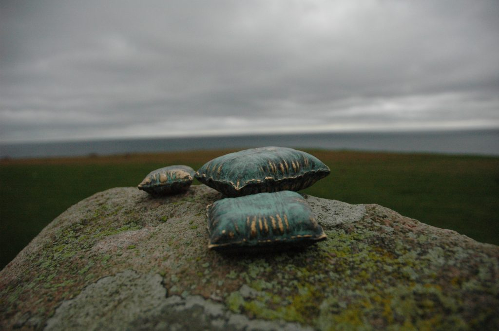 REM består av tre miniatyrskulpturer i brons, formade som kuddar – symboler för övergångar mellan verklighet och dröm. Varje kudde bär på en berättelse om bronsens eviga kretslopp: från konst och kyrkklockor till krigets kanoner, och tillbaka till konsten.

Här vilar drömmar, fångade i bronsens tyngd och tidlöshet, en påminnelse om att det dolda och oupptäckta alltid väntar på att upptäckas.heten att vara den/det man är.

Skulpturen monteras på en aluminiumplatta som fästs med två skruvar. Underlaget behöver en fördjupning, sedan limmas med epoxylim – förslagsvis på sten eller betong.