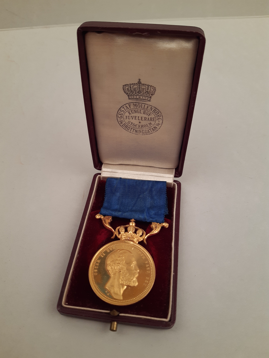 Litteris et Artibus-medalj i guld med blått band, på åtsidan av medaljen finns den regerande Konungens bröstbild och på frånsidan finns inskriften "Litteris et Artibus" omgiven av en öppen lagerkrans. Medaljen är krönt av en sluten kungakrona. Rödbrunt etui i läder med vitt siden på insidan lock och röd sammet på botten.
