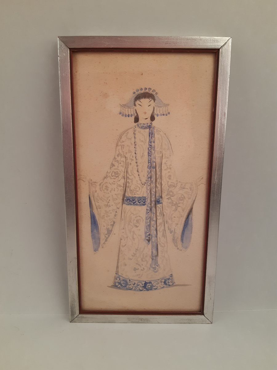 Inramad teckning, kostymskiss, i silverfärgad ram. Föreställer en asiatisk kvinna klädd i kinesisk dräkt i vitt, ljus- och mörkblå. Hon har uppsat svart hår och en blå hårdekoration.
