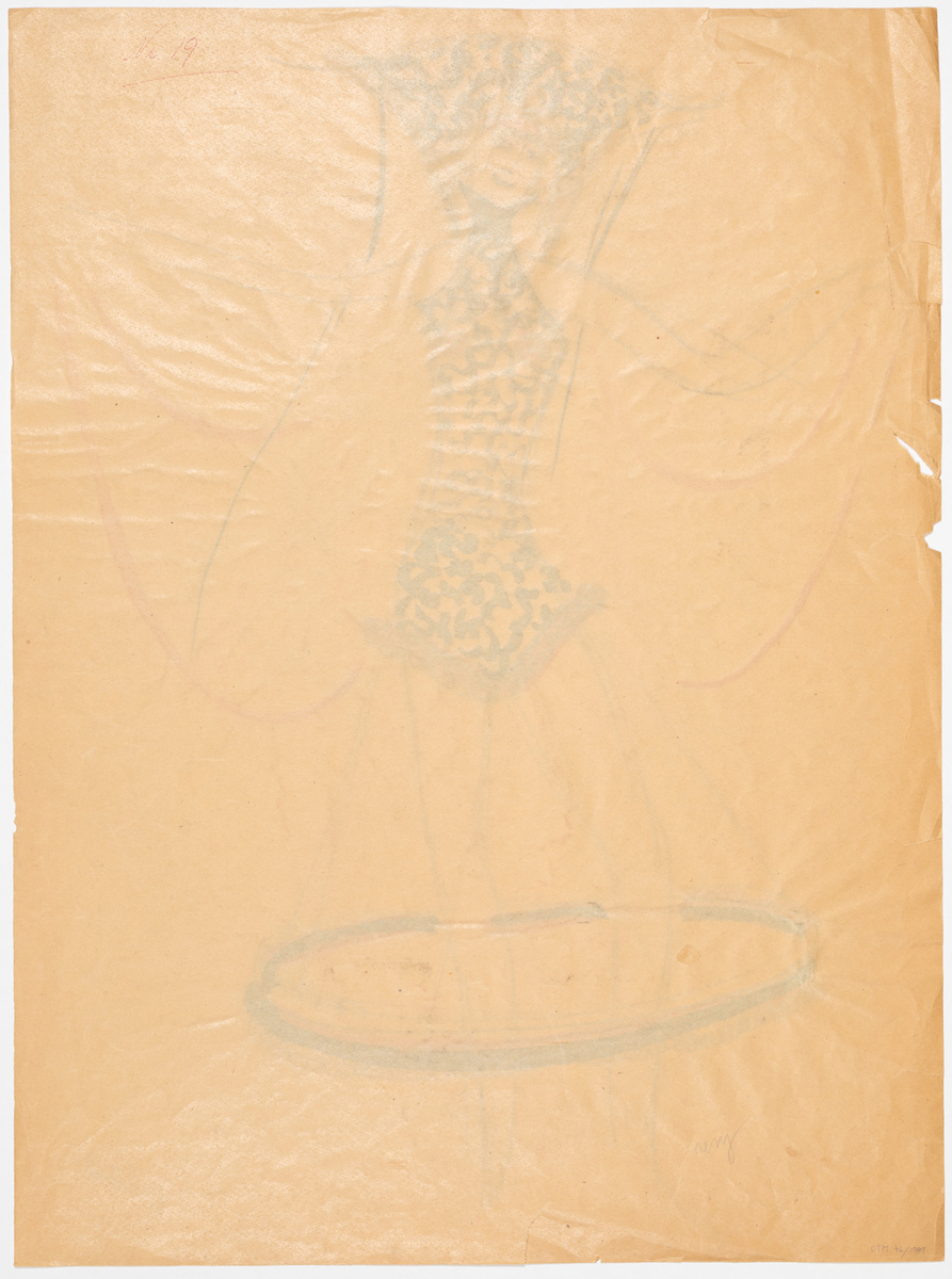 Kvinna i kort kostym i svart och rött. Kostymen har baktill en stor krage från vilken en gul och röd slöja hänger. Runt benen hänger från kostymen en stor ring i svart gult och rött. Runt stt korta blond hår har kvinnan ett rött band.
