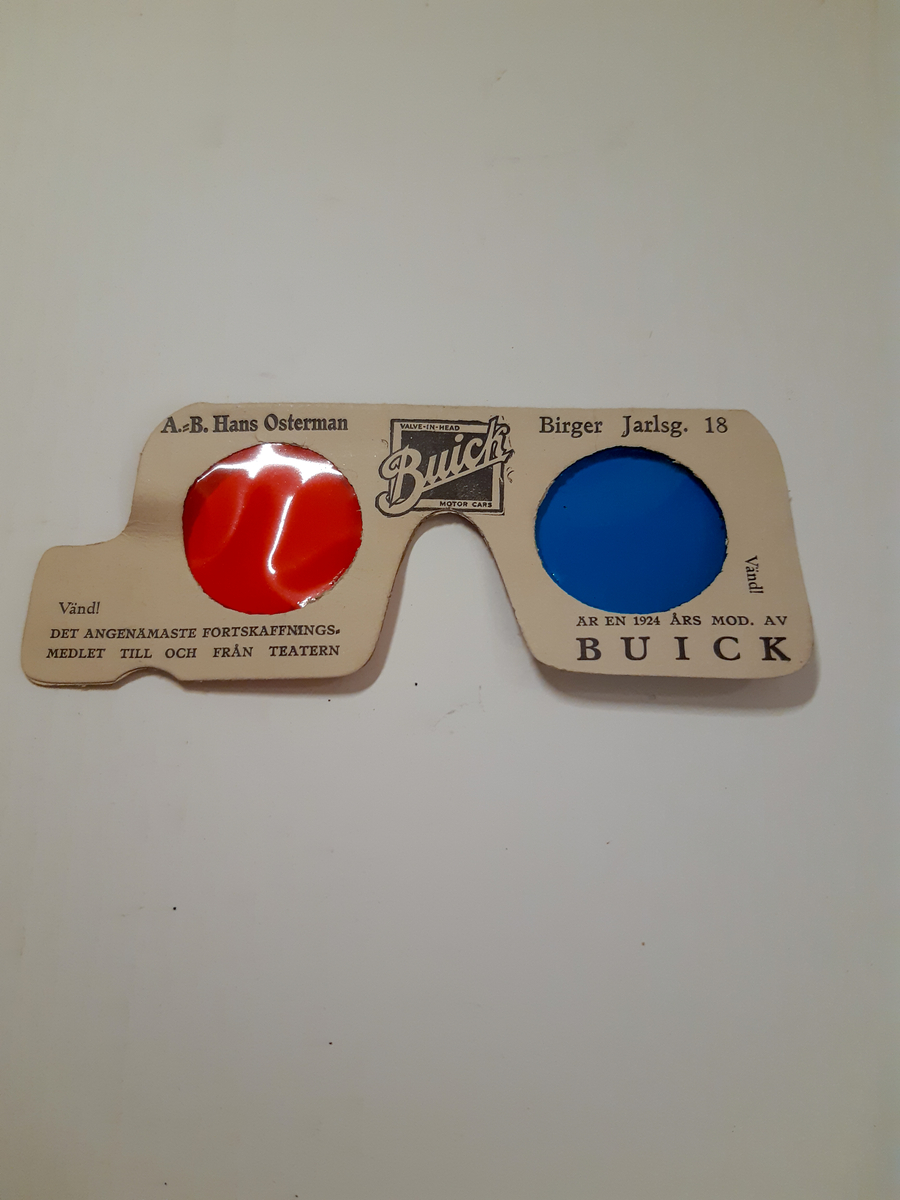 A - Liten röd träklubba med tryck, en torkad liten blomsterbukett och ett visitkort fästade med papperssnöre på ett vishäfte. På vishäftet finns ett stilerat porträtt av Ernst Rolf med konstnärssignatur "E-N" Einar Nerman.
B - Lite ofärgad träklubba med text och ett visitkort fästade med rött sidenband på ett plastetui/hölje för choklad.
C - 3D-glasögon i vit papp med ett rött och ett blått öga i plast. Reklamtext för Buick.
