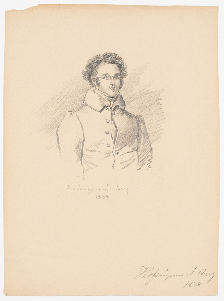 Yngre man med lockigt hår och glasögon. Mannen är klädd i en rock som är delvis knäppt.
