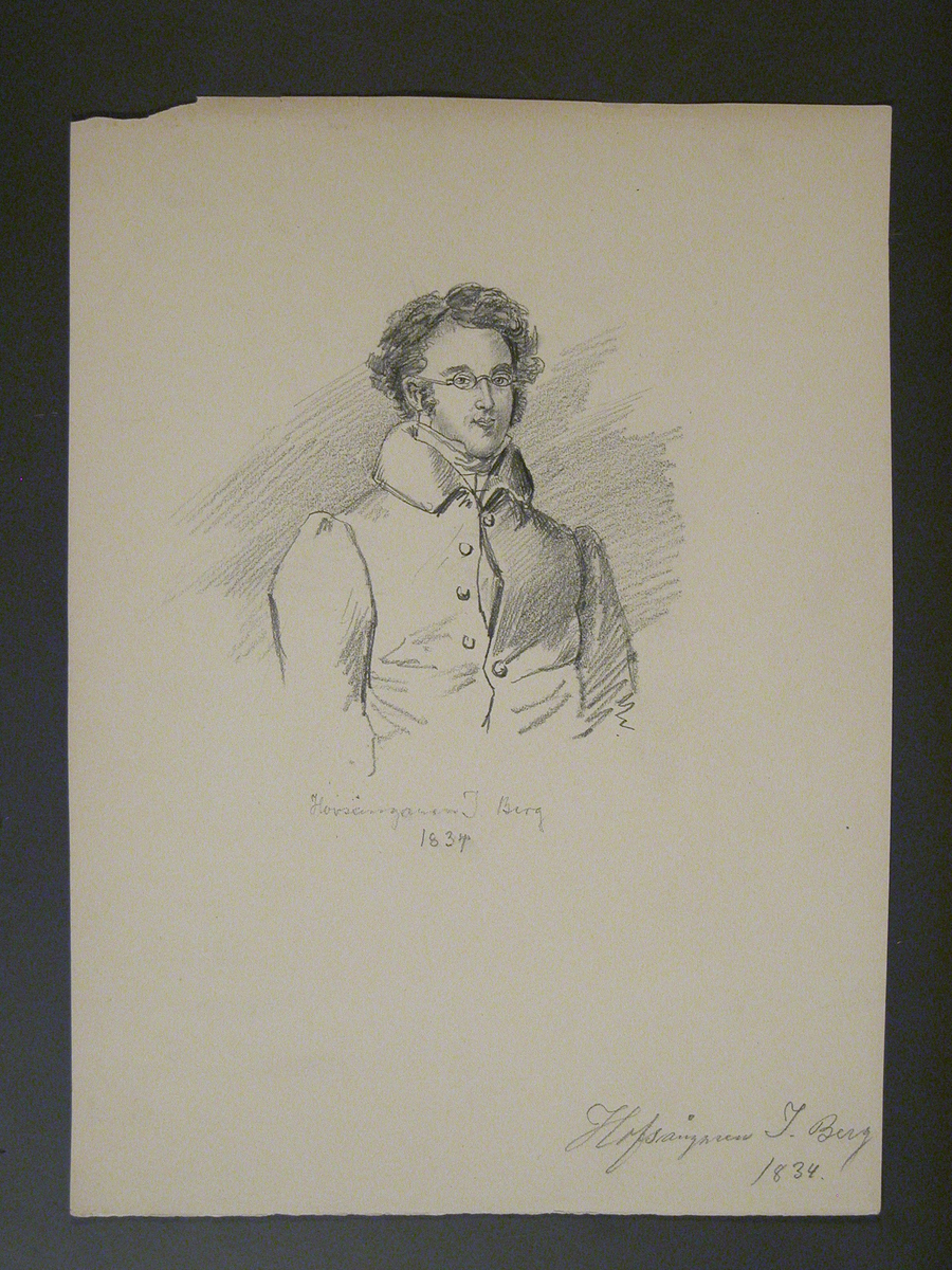 Yngre man med lockigt hår och glasögon. Mannen är klädd i en rock som är delvis knäppt.
