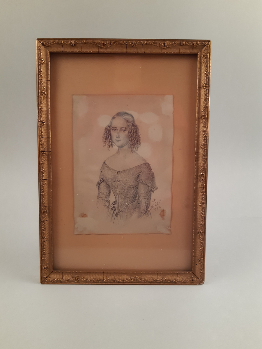 Blyerstteckning föreställande en ung kvinna. Inramad i guldfärgad träram.
