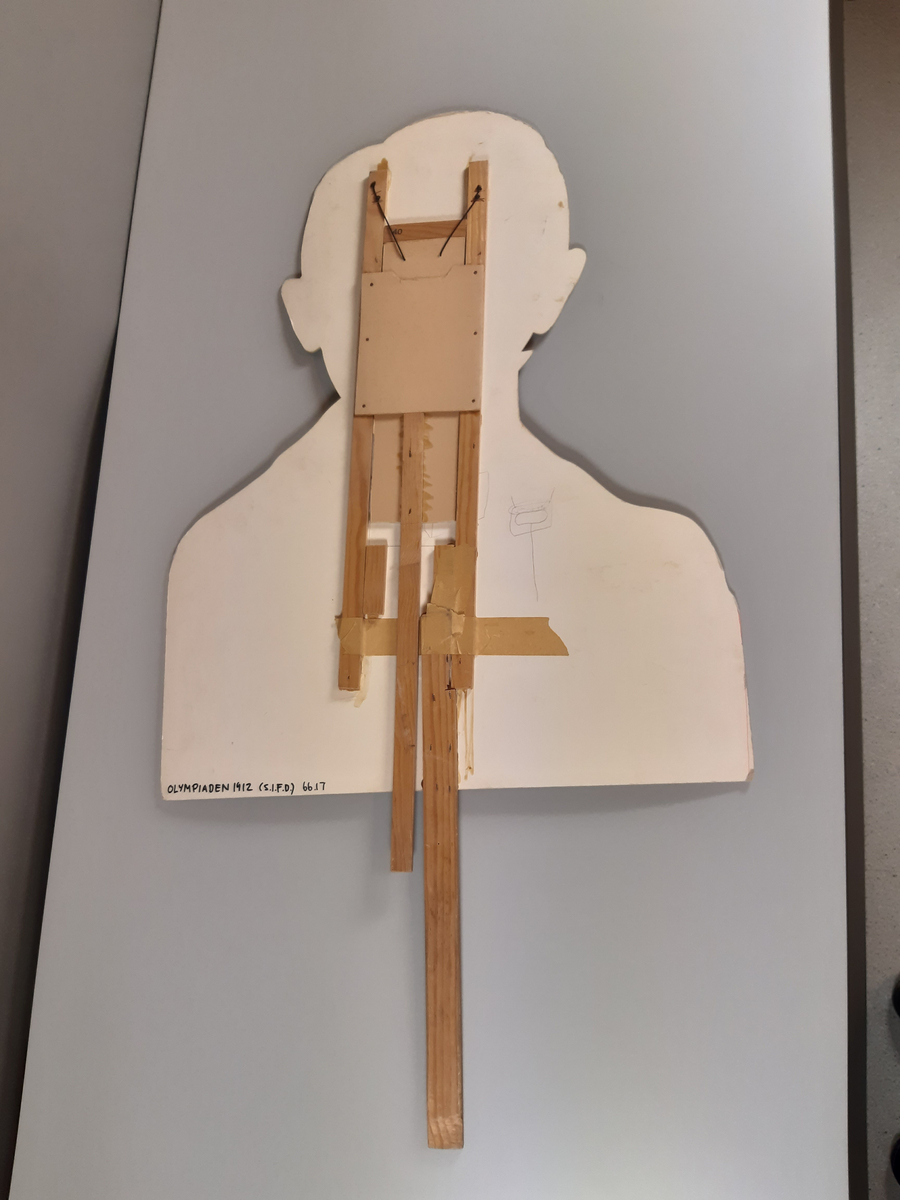 "Pratande" man tillverkad av ett uppförstorat svartvitt fotografi. Huvud, hals och axlar är utklippt. Mannens mun går att öppna och stänga med en träkonstruktion med två handtag på baksidan.
