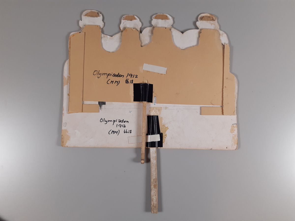 Åtta "pratande" män klädda i mörkgrå kostym målade på tjock kartong. Huvuden, hals och axlar på de fyra översta männen är utklippta. Männens munnar går att öppna och stänga med en träkonstruktion med två handtag på baksidan.
