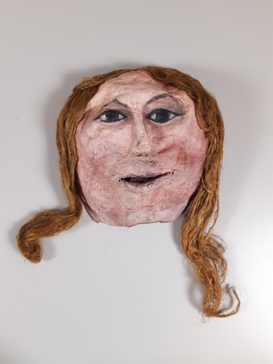 Mask föreställande kvinna med långt hår.
