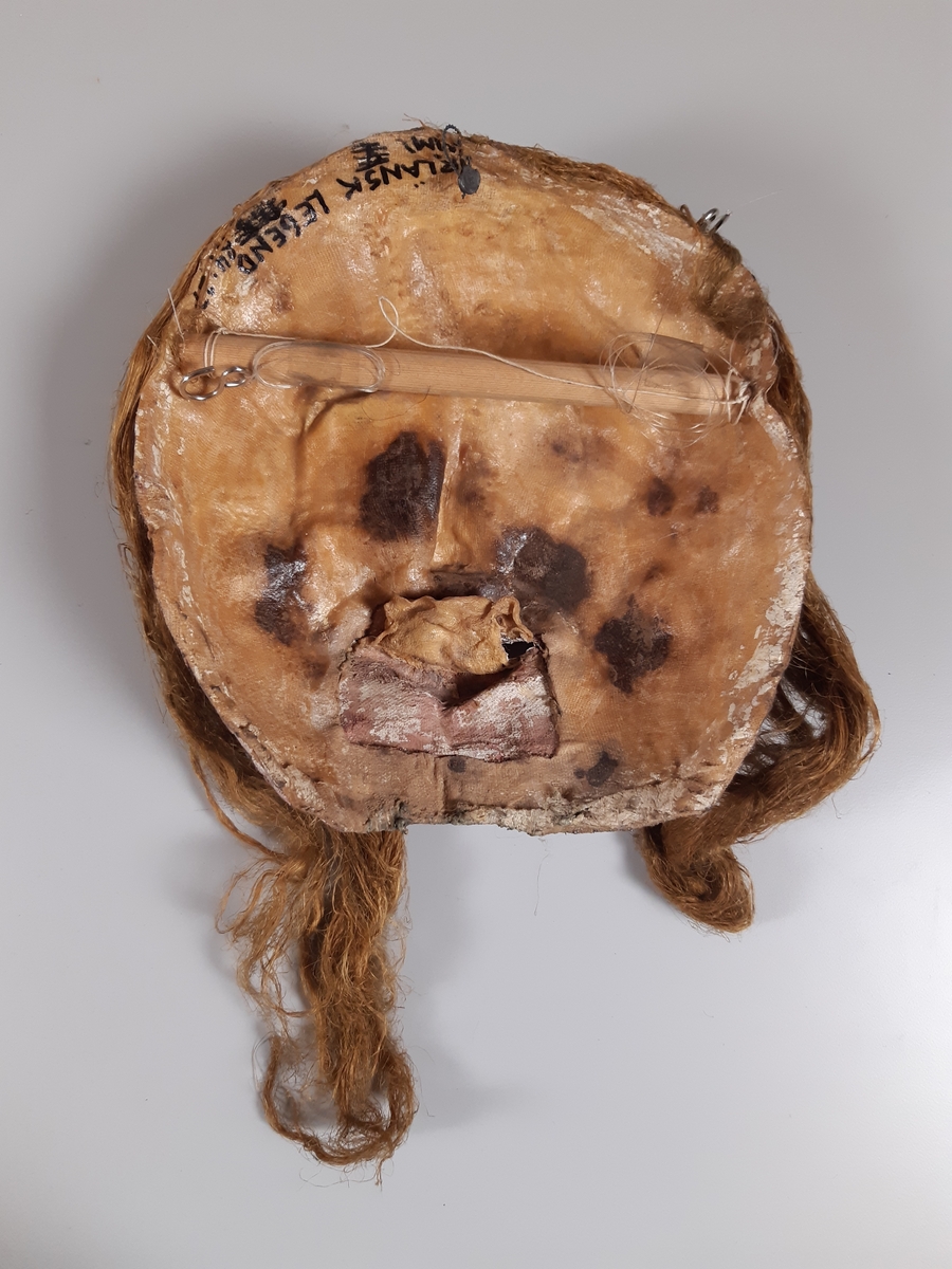 Mask föreställande kvinna med långt hår.
