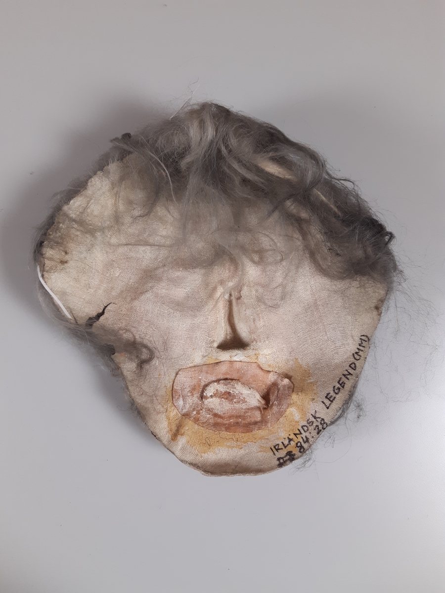 Mask föreställande äldre man med grått hår.
