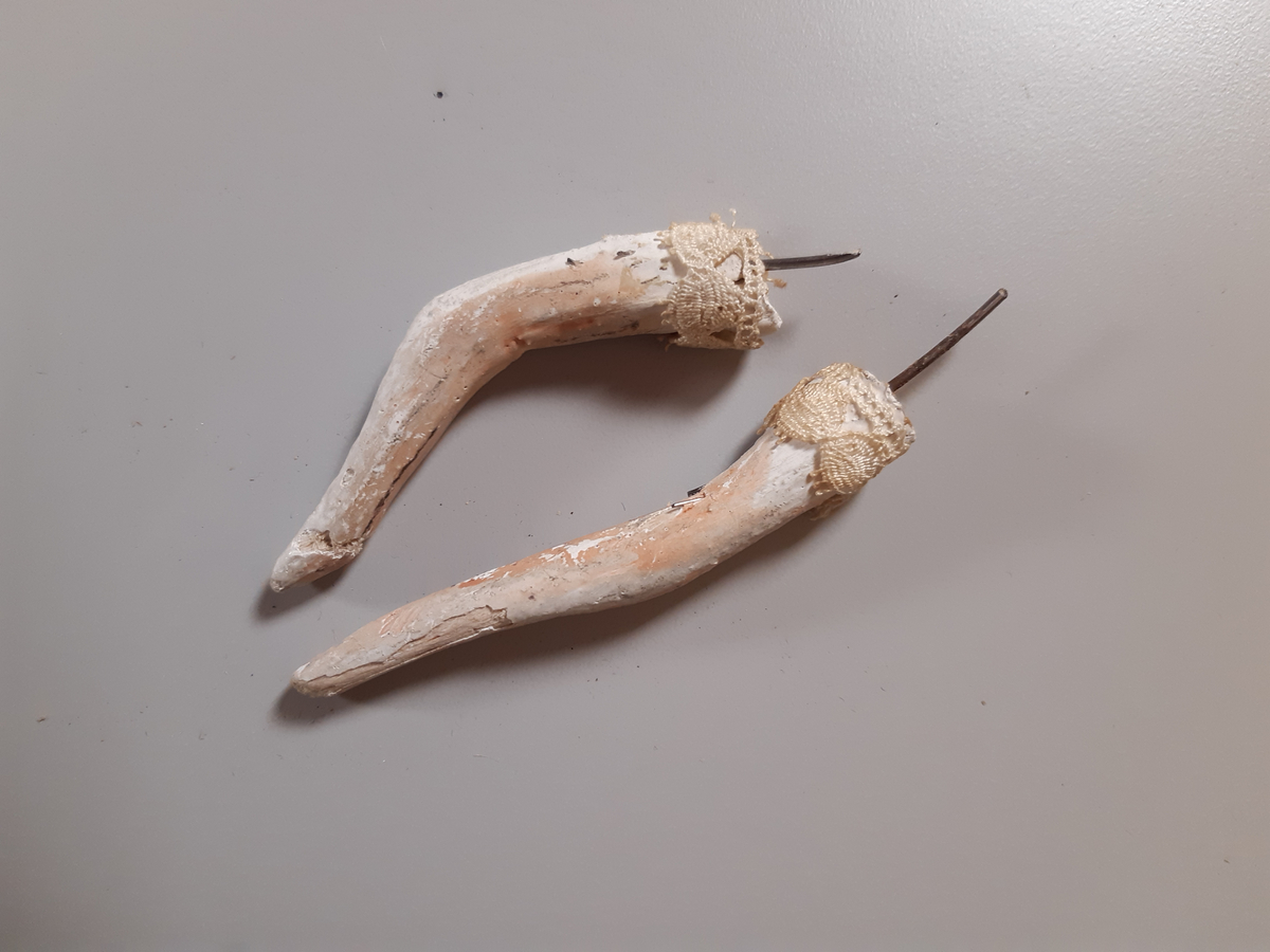 Föreställer en kvinna med vitt hår klädd i vit empirklänning. Dockans armar är lösa. Marionett går att fästa ihop med den andra dockan i dansparet med hjälp av en metallplatta.
