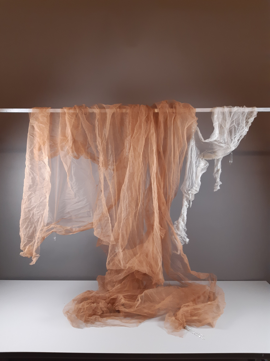 Tyll i ljusbrun, vitt och svart med fästade glaskristaller.
