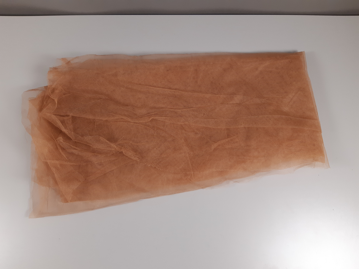 Tyll i ljusbrun, vitt och svart med fästade glaskristaller.
