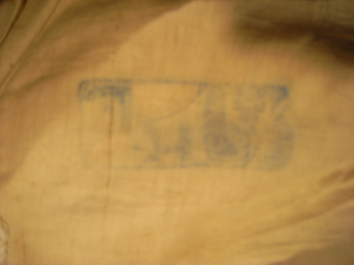 Jacka av kläde i en ljusgrå färg med långa ärmar av mönstervävt tyg i gul färg. Jackan har längre skört, knäppning mitt fram med runda tätt sittande guldfärgade knappar, markerade axelvingar. Dekorband i guldfärg, sammetsband i röd färg samt snoddar i ljusgrå färg.
