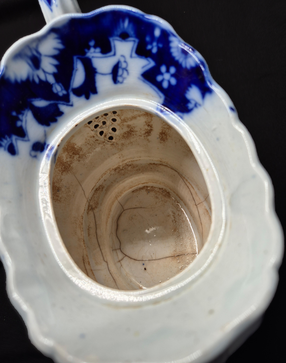 Tekanna, med lock, fajans. Blå kinesimiter mot vit bakgrund. Diverse lagningar med zinkklamrar. 