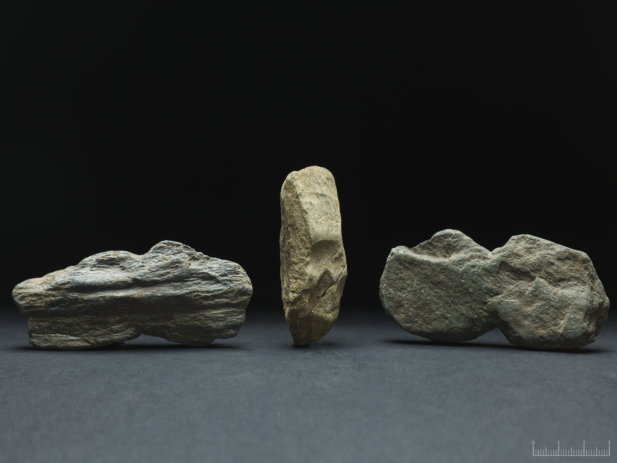 To flate søkker av skifrig bergart, tilfeldige i formen og med innhakk rundt midtpartiet for feste. 